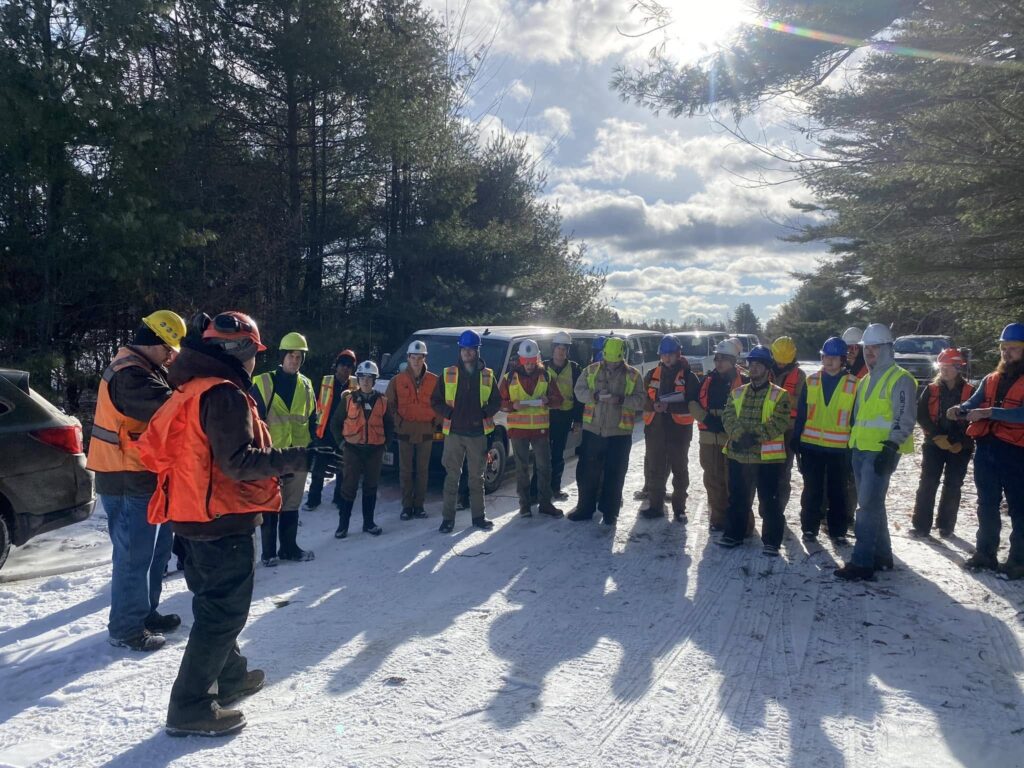 A photo of more than 20 participants listening to instructions at a Northeast Master Logger Certification training held outdoors in January 2024