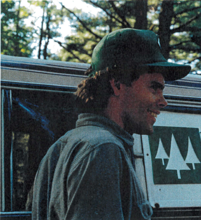 NEFF forester Mike Burke stands beside a NEFF-branded vehicle in a forest setting